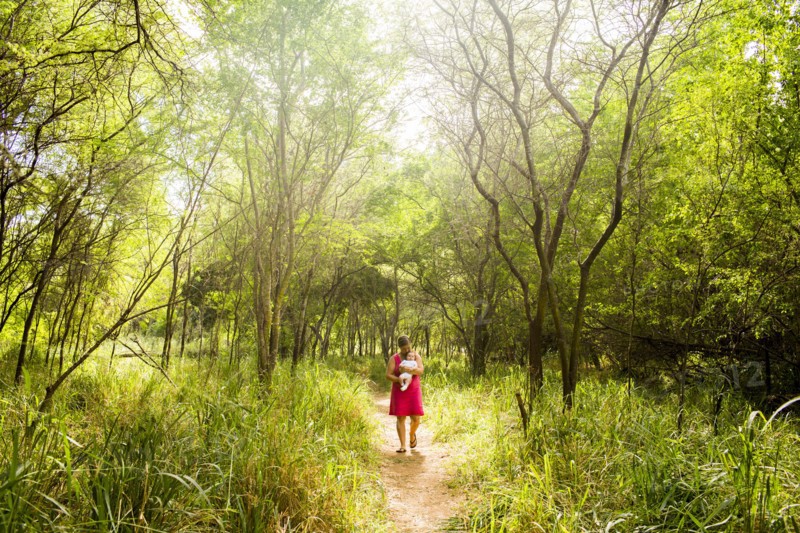 Caucasian woman carrying baby in lush jungle