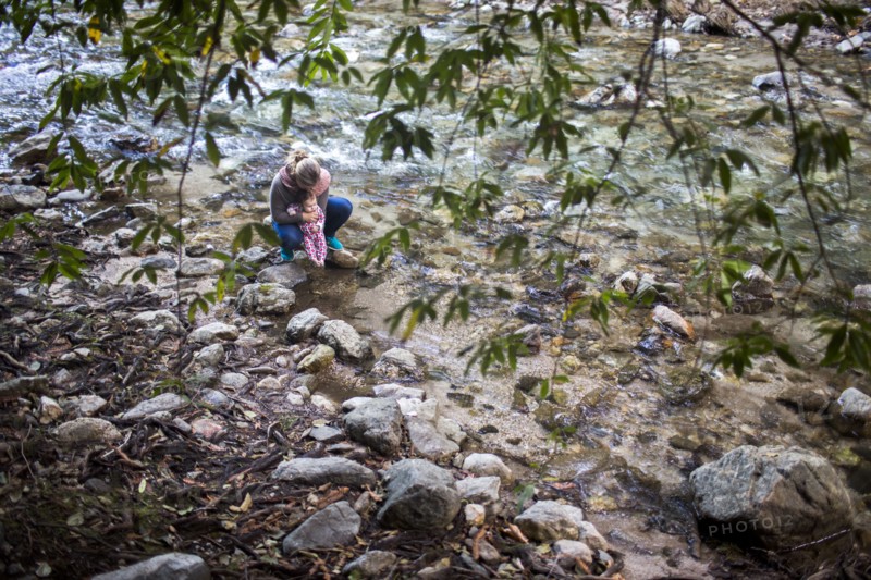 High angle view of Caucasian mother and baby at rocky river