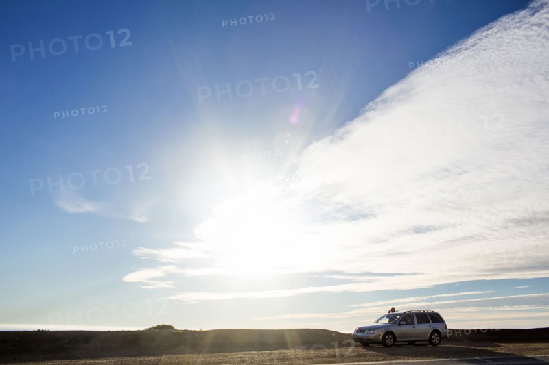 Sunshine and clouds over car on roadside