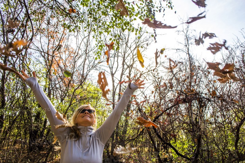 Caucasian woman throwing autumn leaves in forest