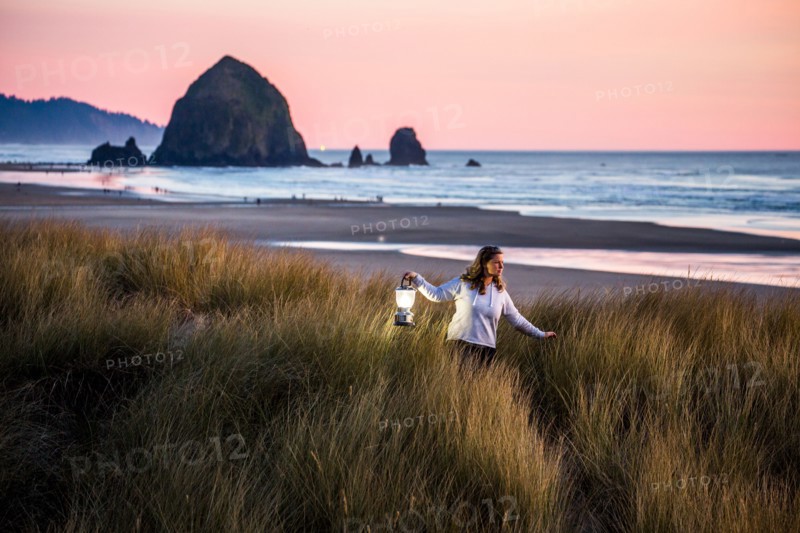 Caucasian woman carrying lantern on Cannon Beach