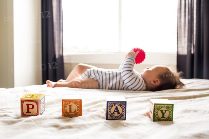 Caucasian baby girl playing on bed