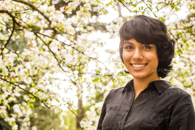 Hispanic woman smiling under trees
