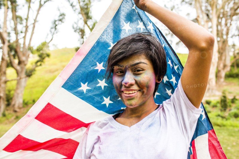 Hispanic woman covered in pigment powder holding American flag