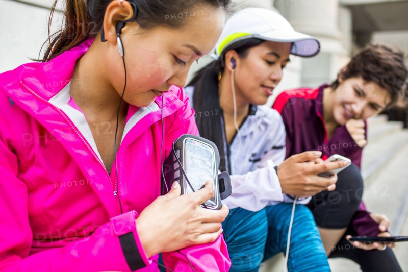 Runners using cell phones and earbud on city sidewalk