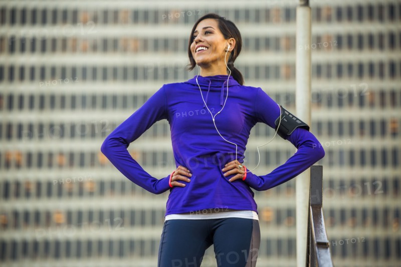 Hispanic runner standing near highrise building