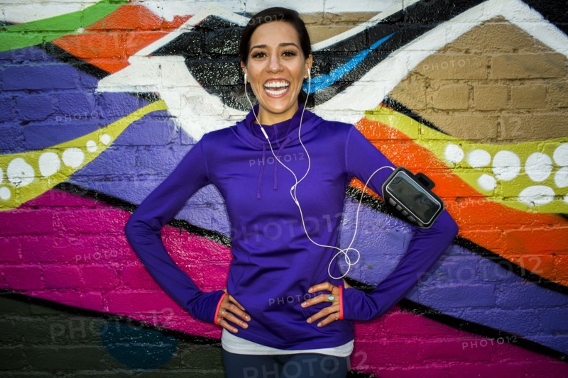 Hispanic runner smiling near graffiti wall