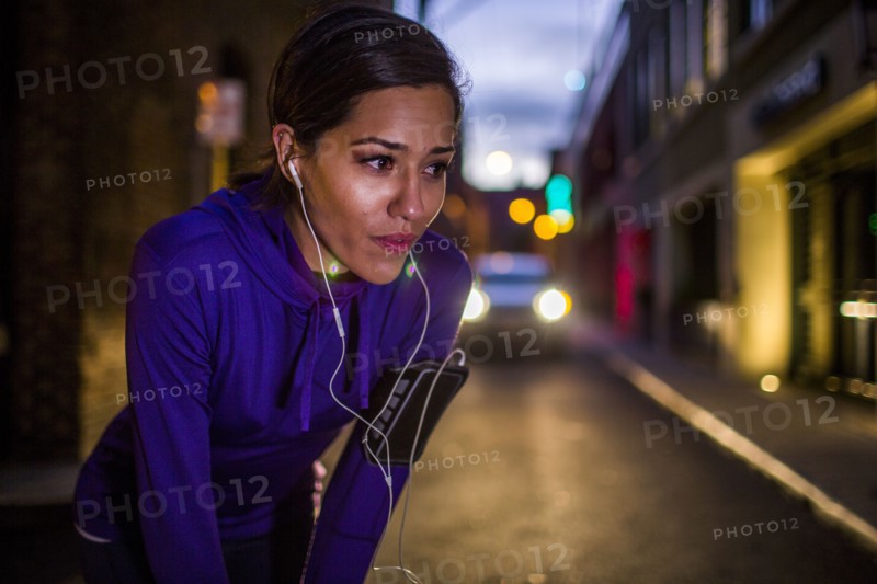 Hispanic runner resting on city street at night