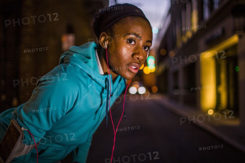 Black runner resting on city street at night