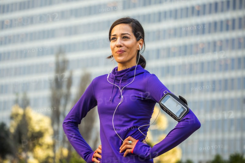 Hispanic runner standing near high rise building