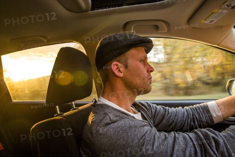 Caucasian man driving car at sunset