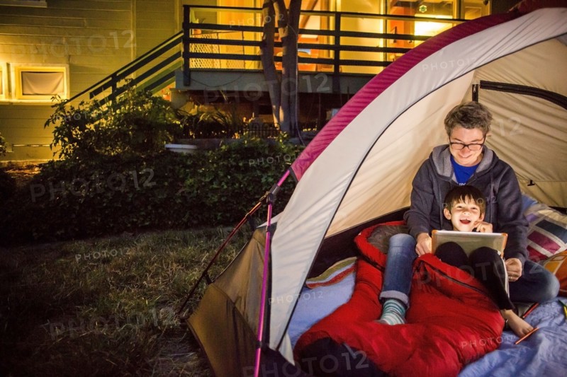 Mother and son using digital tablet in backyard tent