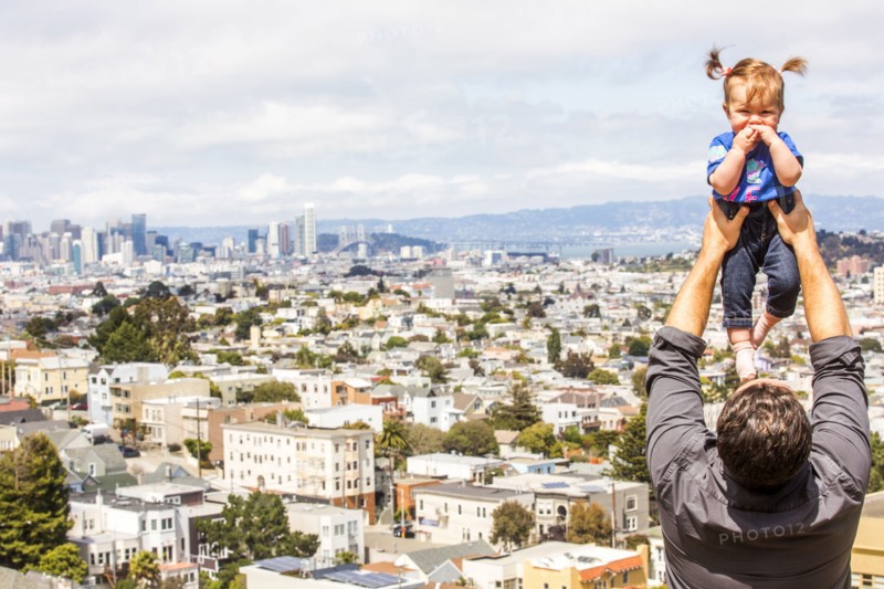 Caucasian father lifting daughter over San Francisco cityscape