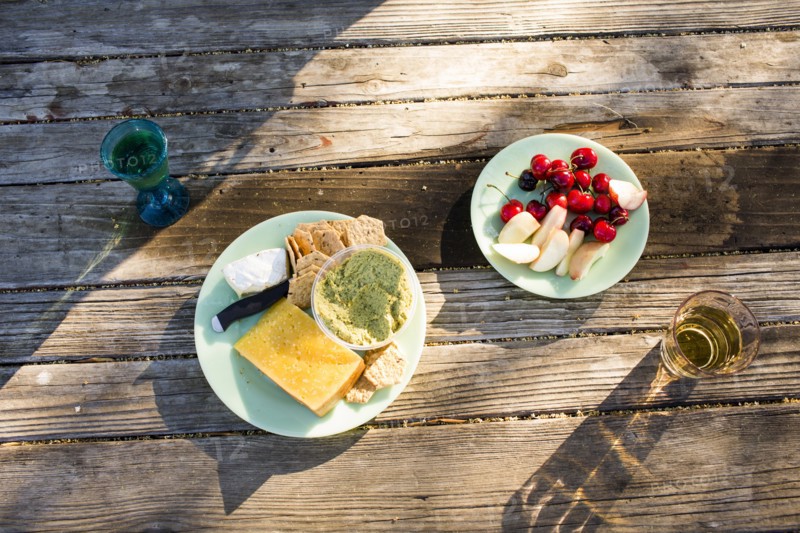 Plates of cheese and fruit on wooden table