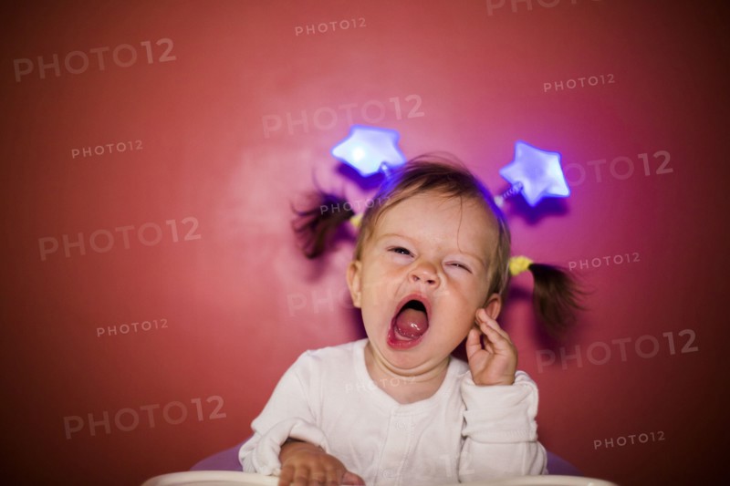 Caucasian baby girl wearing headband with stars and yawning