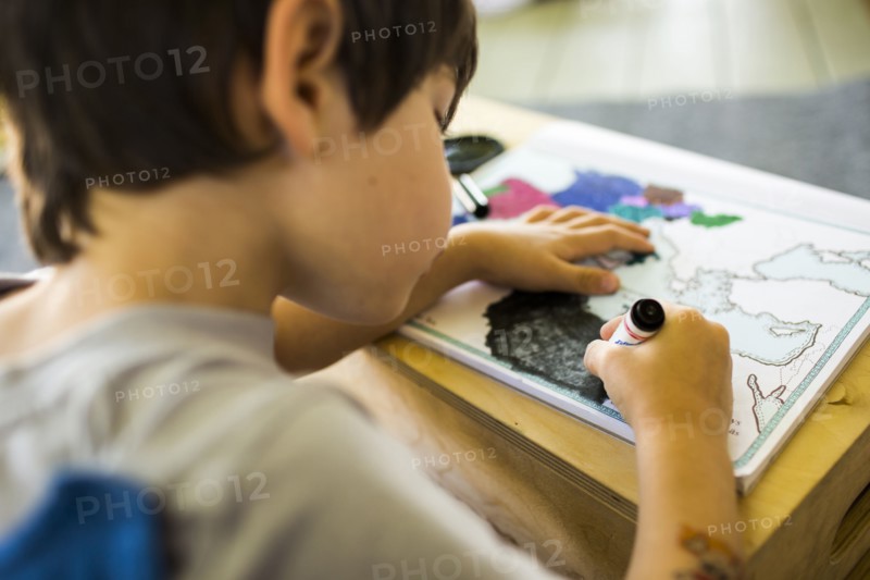 Mixed race boy coloring map with crayon