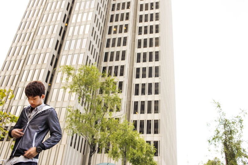 Asian man standing near urban skyscraper