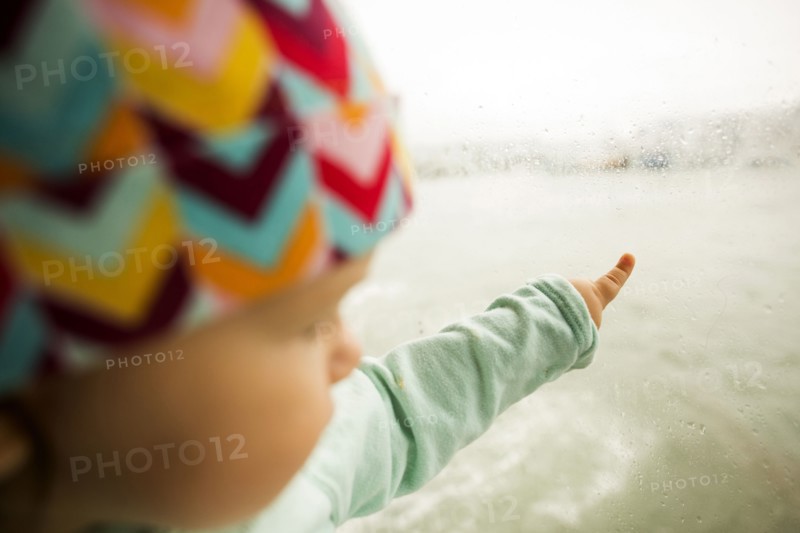 Caucasian baby girl pointing at ocean from window