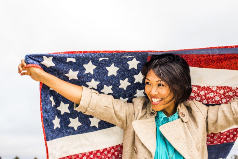 Woman holding American flag quilt outdoors