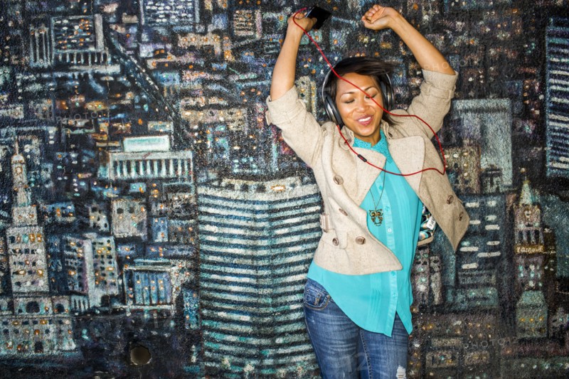 Woman dancing to headphones by mural