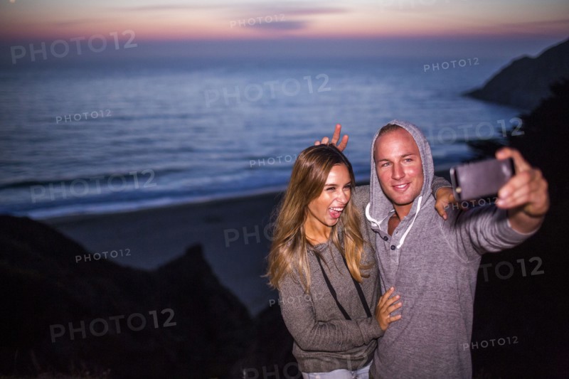 Caucasian couple taking selfie at beach