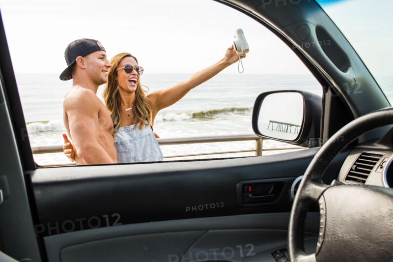 Caucasian couple taking selfie at beach