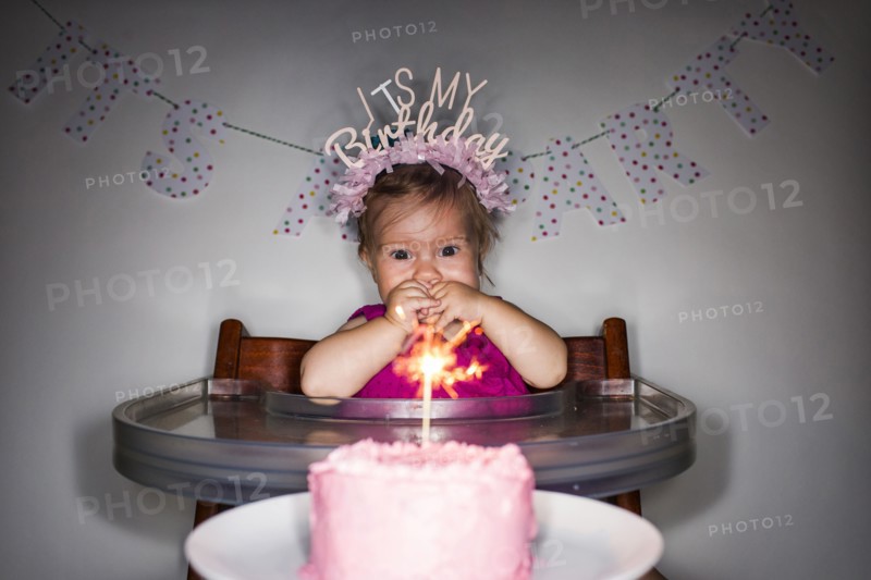 Caucasian baby girl admiring birthday cupcake