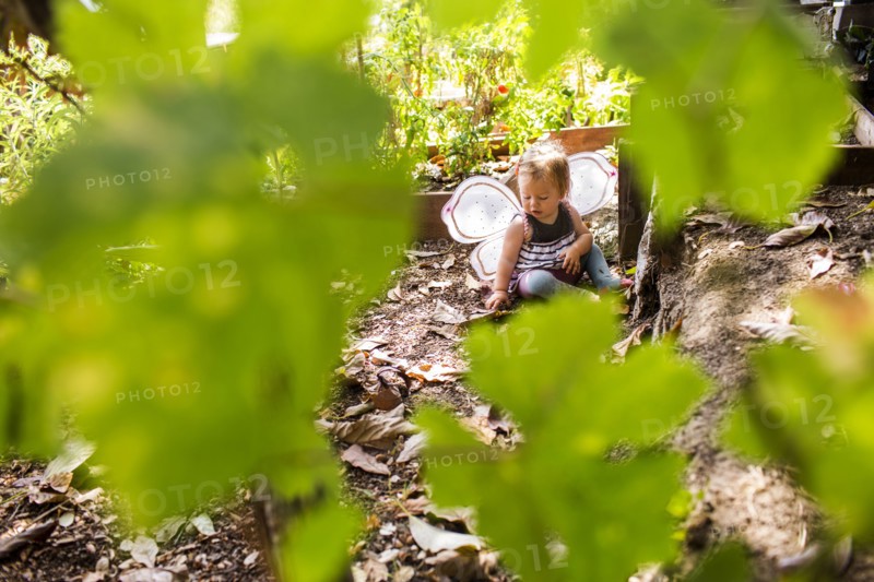 Caucasian baby girl wearing fairy wings in garden