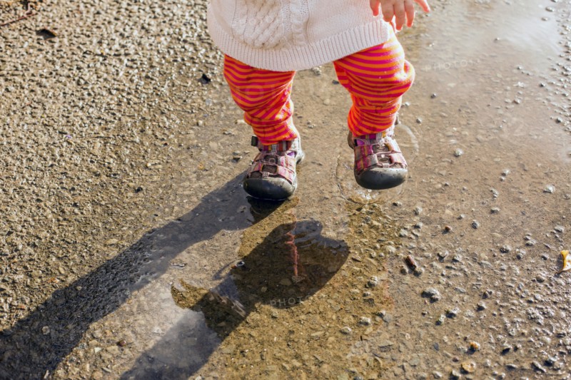 Caucasian baby girl walking in puddle