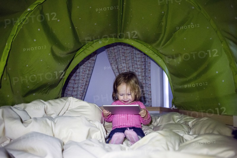 Caucasian baby girl using digital tablet in tent