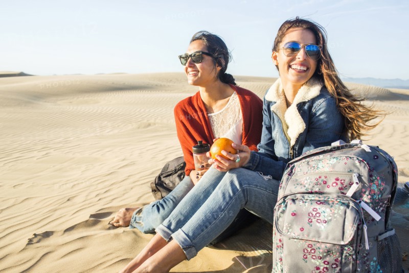 Mixed race women sitting on sand dunes