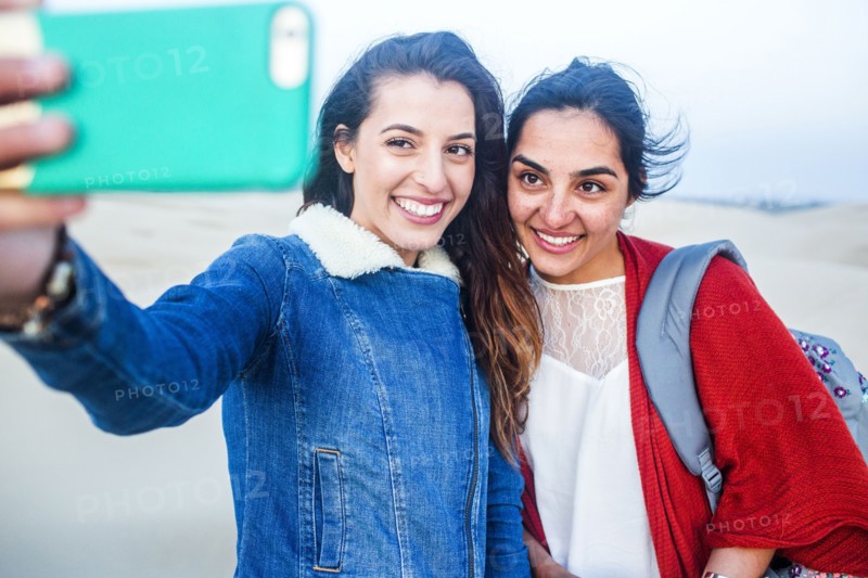 Mixed race women taking selfie on beach