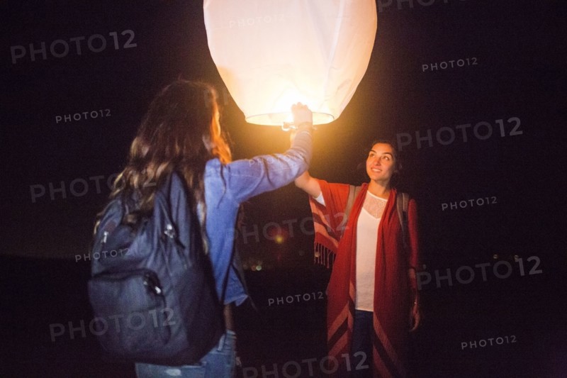 Mixed race women floating lantern at night