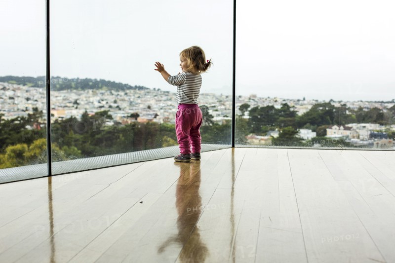 Curious Caucasian girl leaning on window admiring cityscape