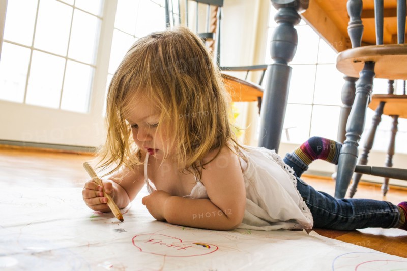 Caucasian girl laying on floor drawing on paper