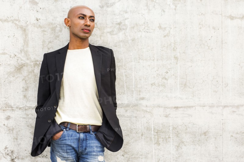 Pensive gay Black man leaning on concrete wall