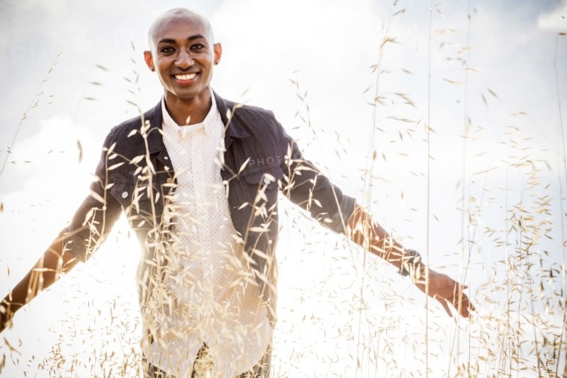 Smiling gay Black man standing in tall grass