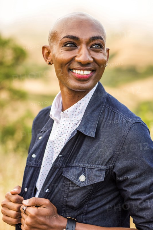 Smiling gay Black man holding denim jacket