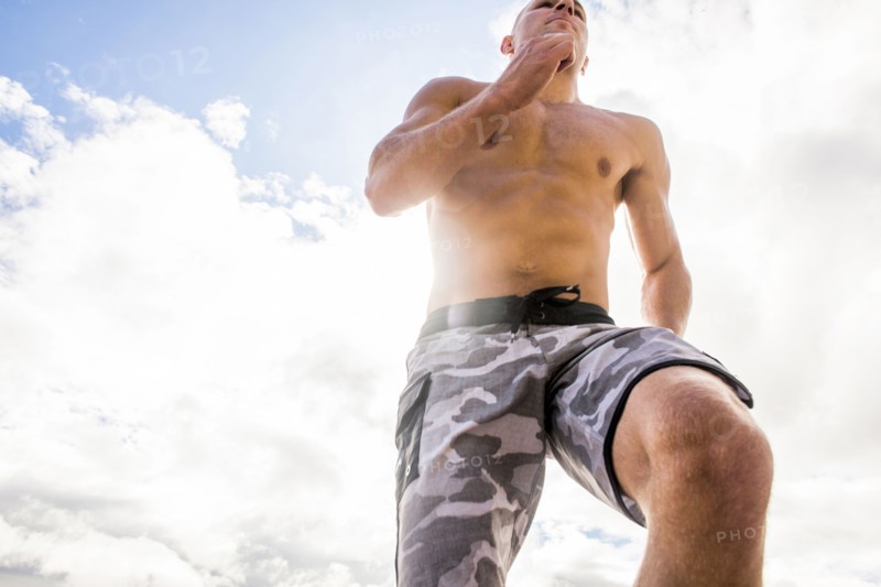 Caucasian man with bare chest running under cloudy sky
