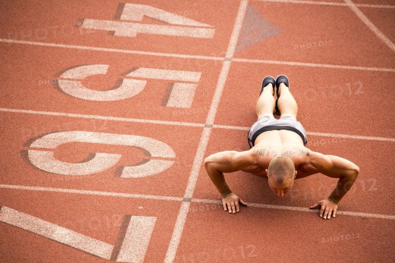 Caucasian man doing push-ups on running track