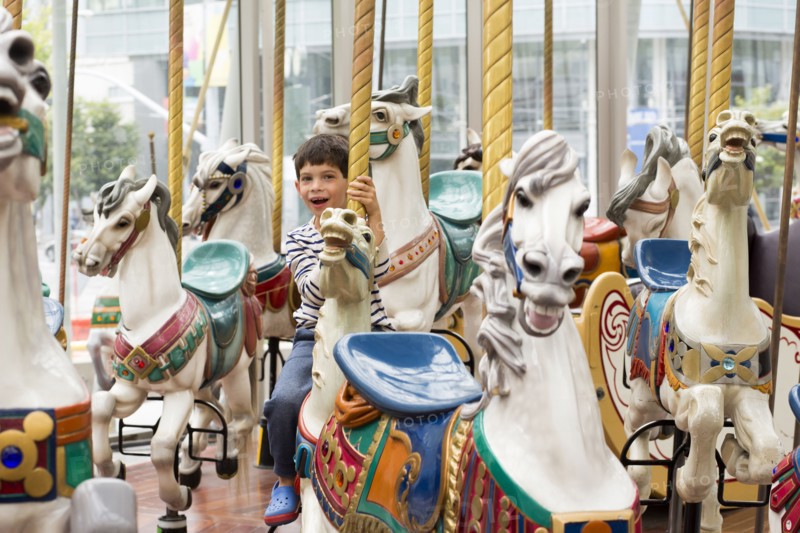 Mixed race boy riding carousel