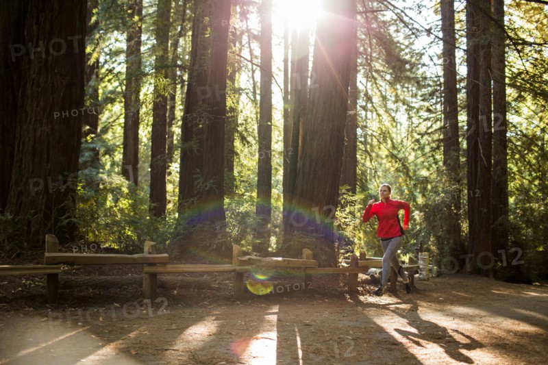 Woman running on sunny forest path