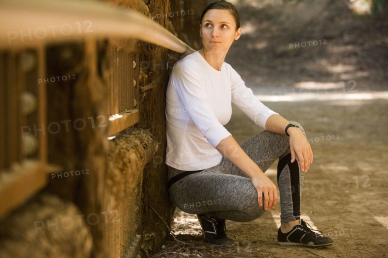 Curious woman crouching on forest path