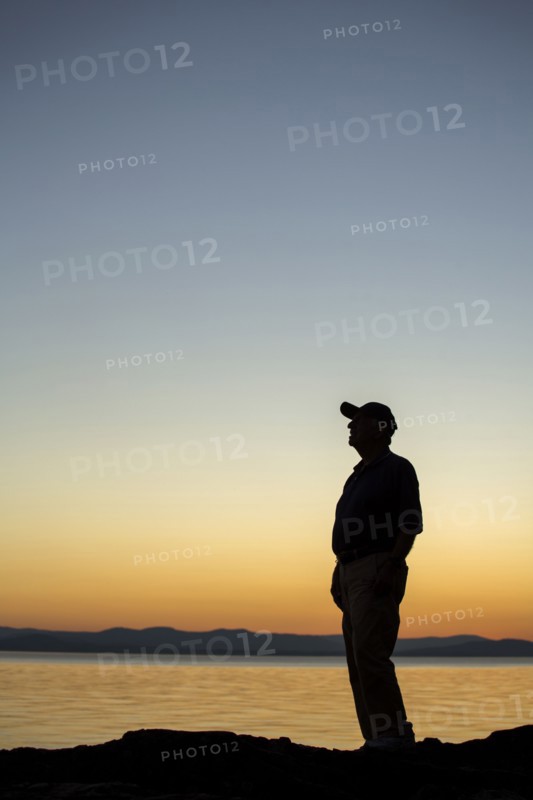 Silhouette of Caucasian man near water at sunset