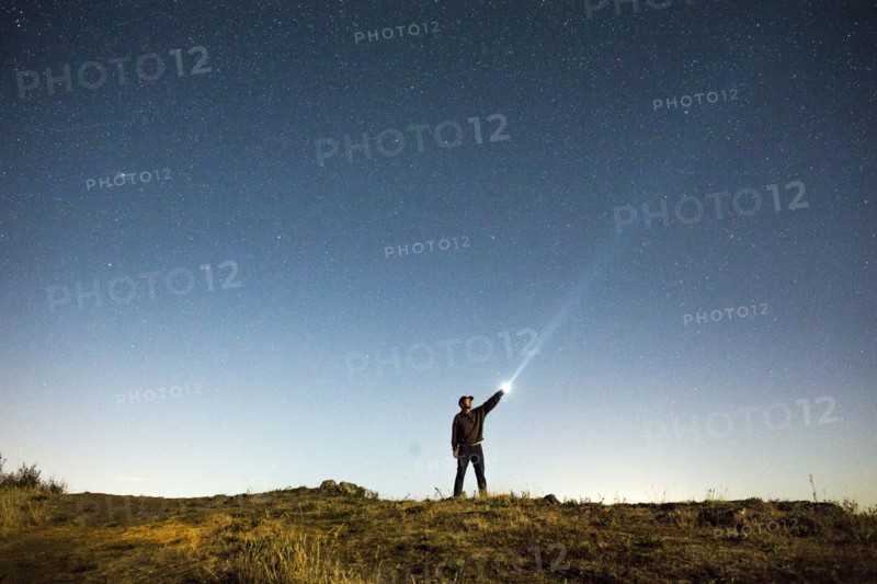 Caucasian man pointing flashlight at night sky