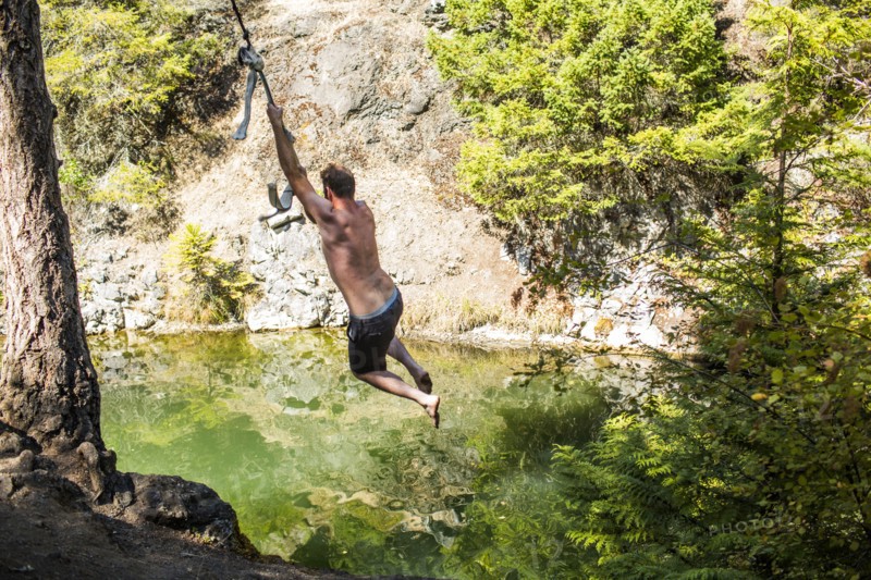 Caucasian man swinging on rope over water