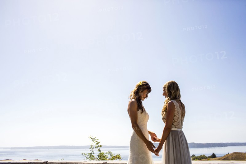 Caucasian brides holding hands at waterfront