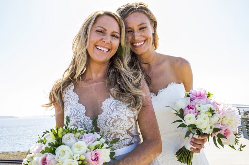 Smiling Caucasian brides holding bouquets