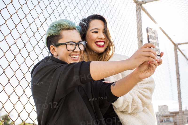 Smiling Asian women posing for cell phone selfie