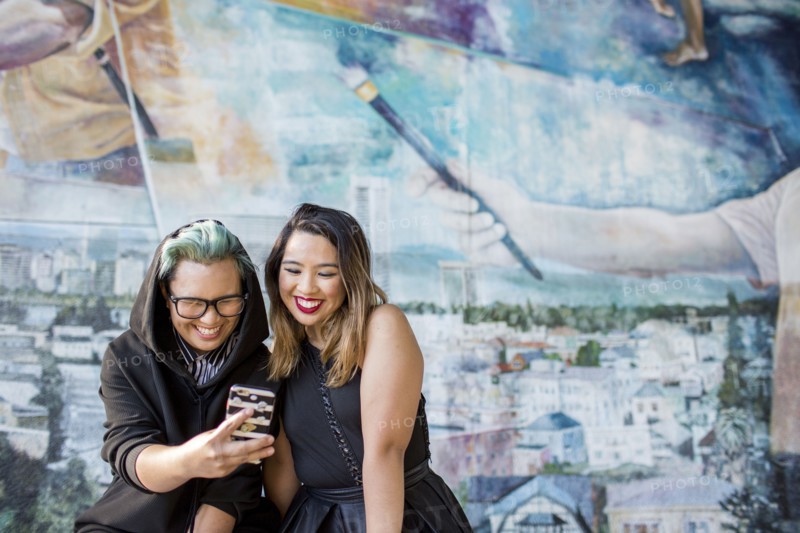 Smiling Asian women posing for cell phone selfie